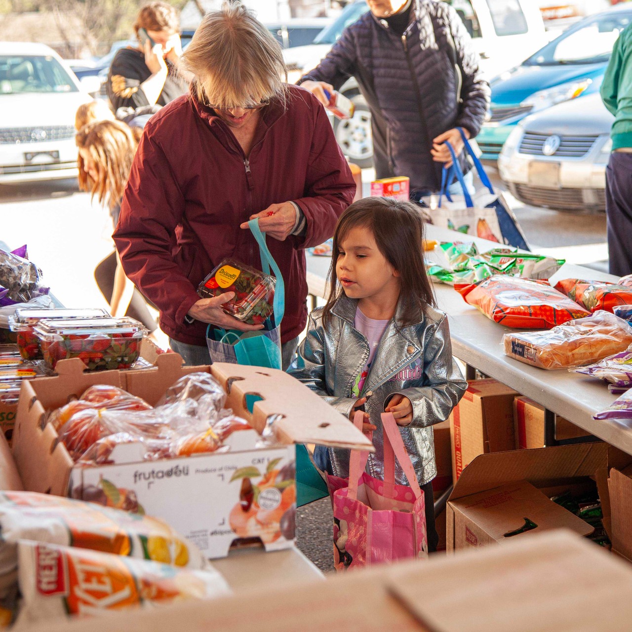 Woman and child selecting food from an outreach. The food pictured is fresh produce and pastries.