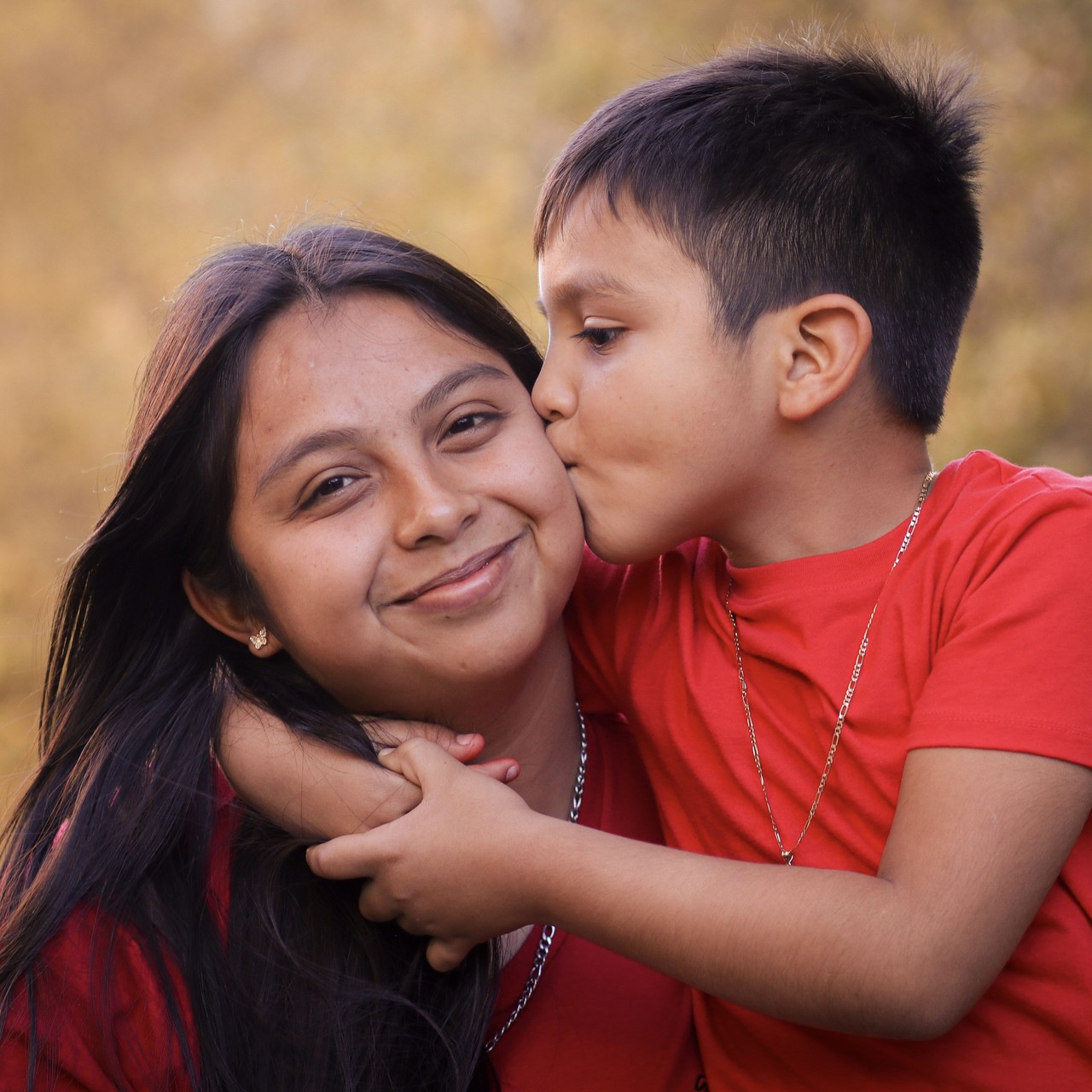 Mother holding young boy while he kisses her on the cheek.
