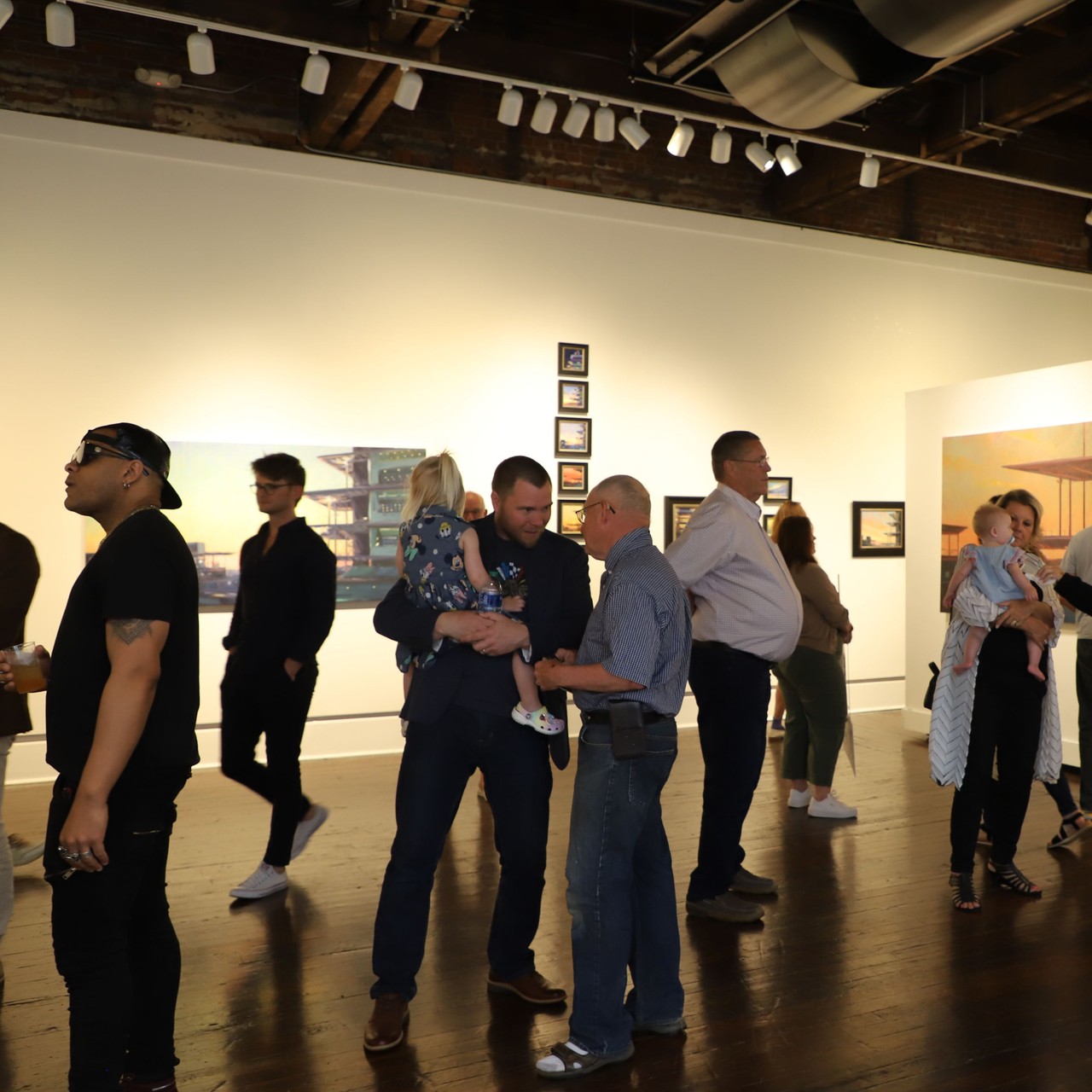 A diverse, multi-generational group of people looking at art in a gallery