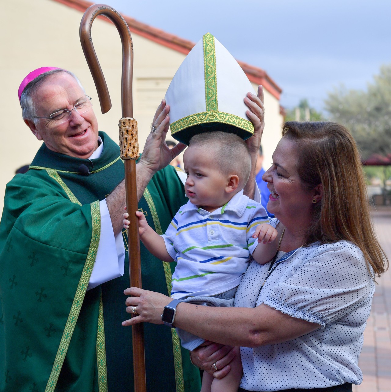 This image shows Bishop John Dolan in placing the Bishop's miter on a baby.